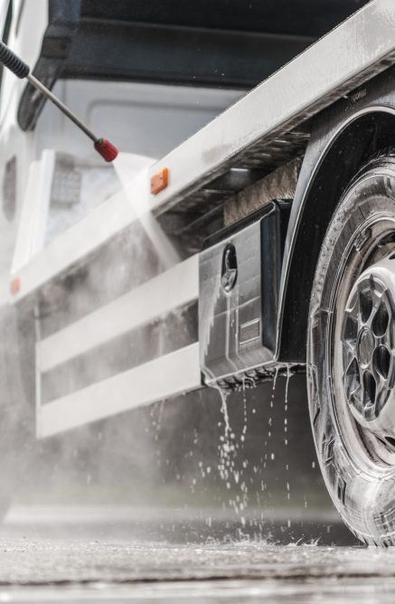 Towing Truck Outdoor Pressure Washing Caucasian Repo Company Worker Pressure Washing His Towing. Repossession Industry Theme.